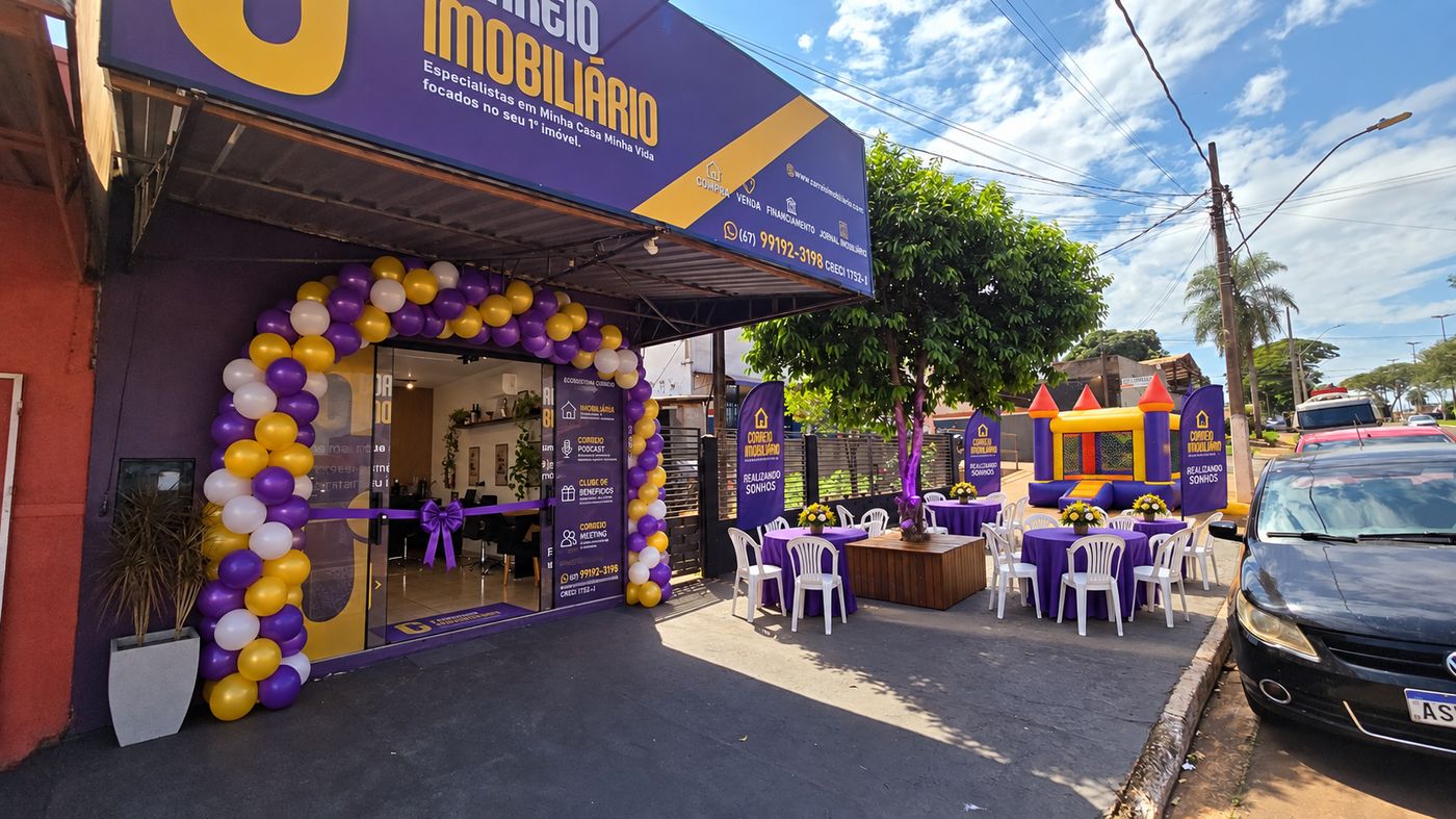 Fachada do Correio Imobiliário decorada com balões roxos, amarelos e brancos no dia da inauguração