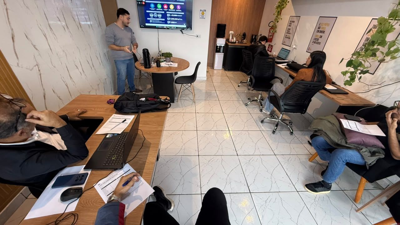 Equipe em treinamento na sala do escritório, com apresentação na TV